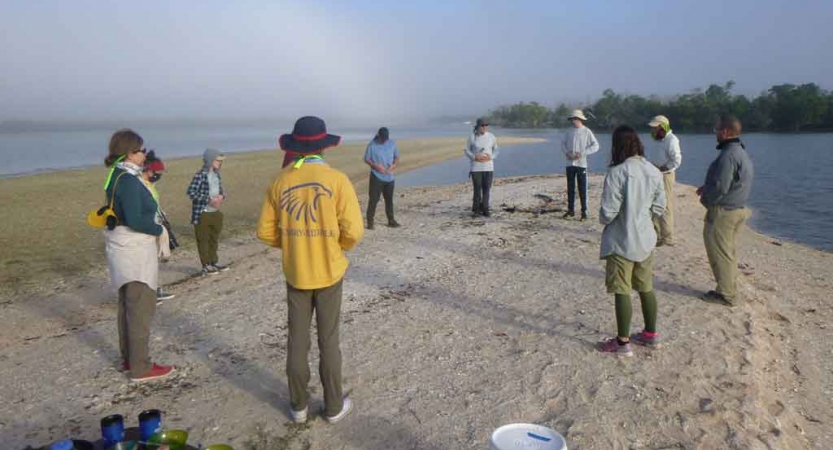 a group of families stand on a beach during a canoeing exercise on an outward bound trip